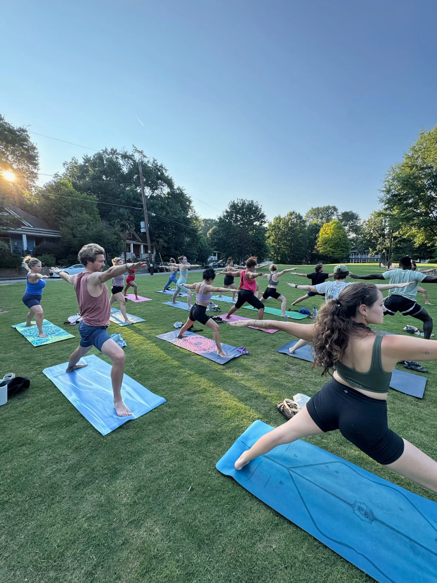 Outdoor amiqo Park Flow yoga class holding warrior pose at sunset
